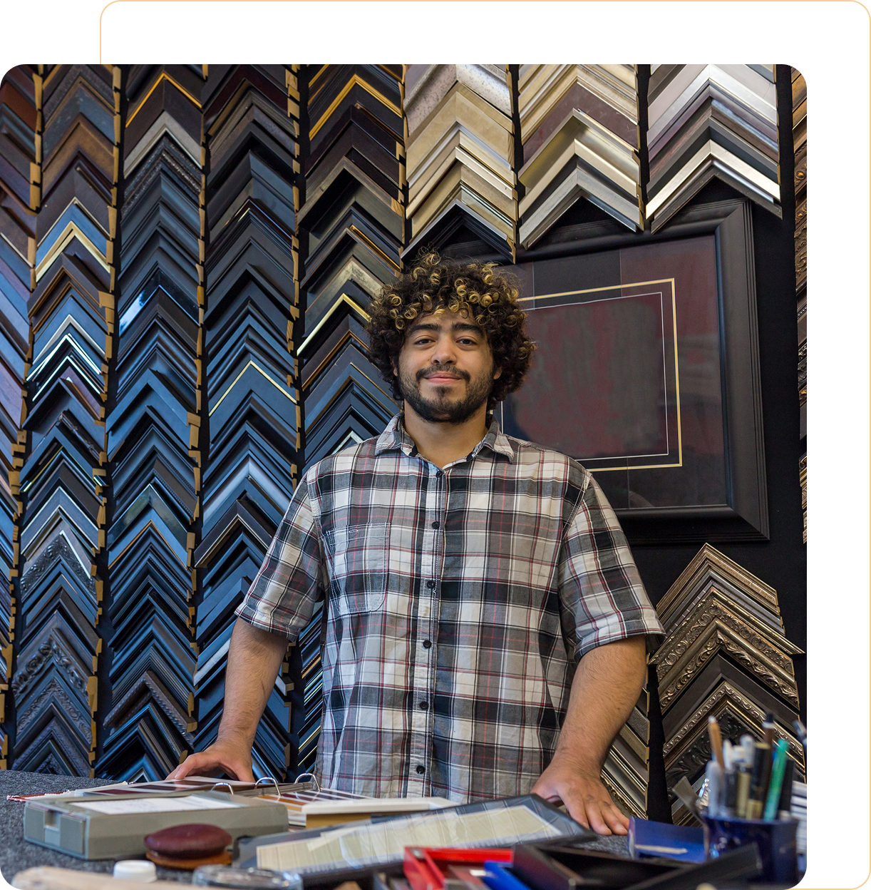 Man standing in frame shop with samples.