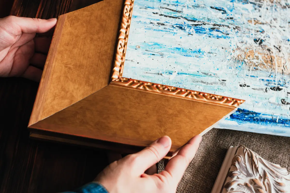 Hands holding ornate wooden picture frame.
